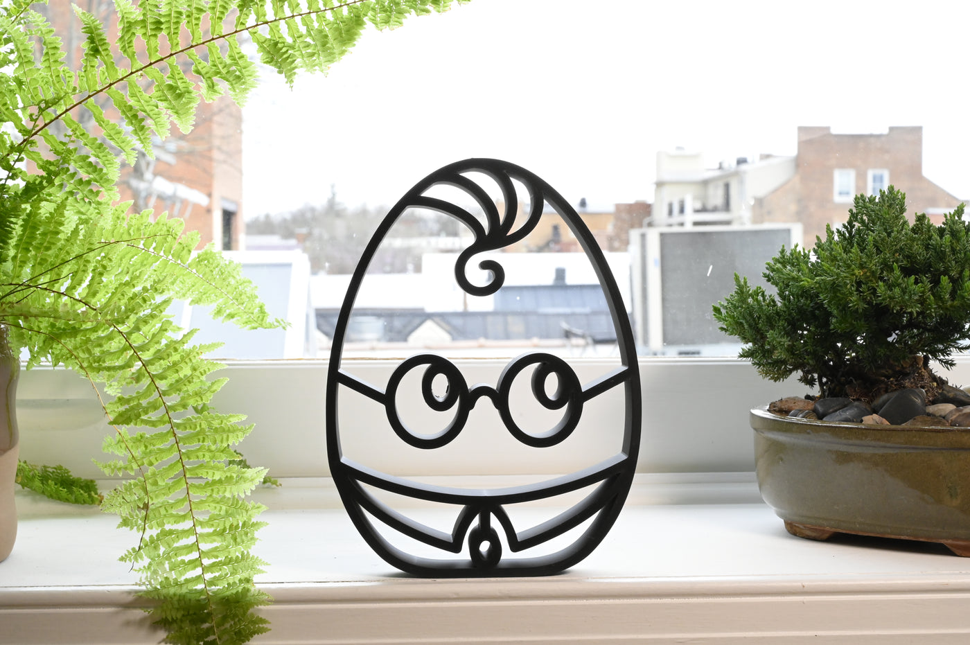 Previous black freestanding Boy Wizard Easter egg line-art sculpture lifestyle image.