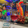 Wine glass and Shenandoah Uncorked event card with colorful sculptures in the background