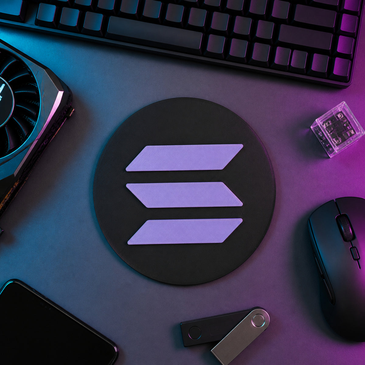 Black and purple circular Solana crypto logo sign displayed flat on a neon-lit trader desk beside a keyboard, hardware wallet, and technical equipment.